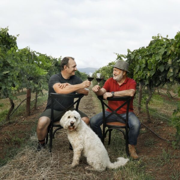 Hunter Valley Winemaker Mike De Iuliis and his Dad Joss De iuliis celebrate in a vineyard with the groodle Lucy